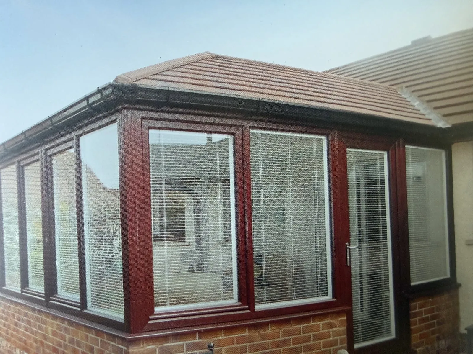 Wide white conservatory completed with a lightweight grey tiled roof
